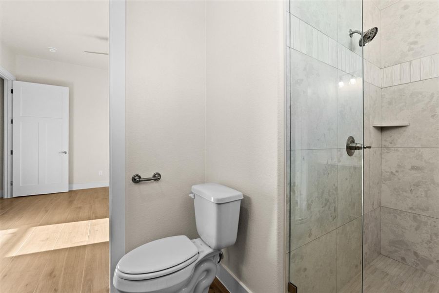 Full bath with wood finished floors and a shower stall