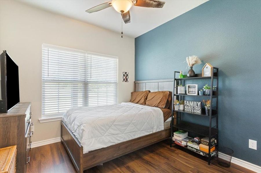 Bedroom featuring dark wood finished floors, a ceiling fan, and a textured wall