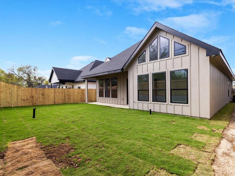 Rear view of property with board and batten siding, a patio area, a shingled roof, and a fenced backyard