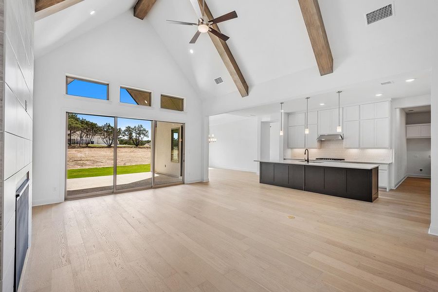 Unfurnished living room with high vaulted ceiling, recessed lighting, light wood-style floors, ceiling fan, and beam ceiling