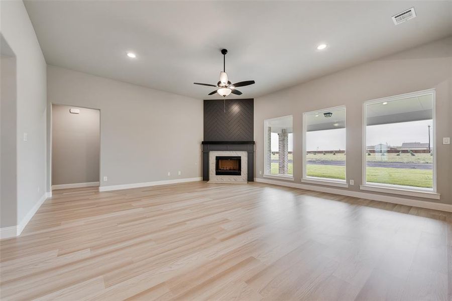 Unfurnished living room featuring light wood-type flooring, a premium fireplace, and ceiling fan