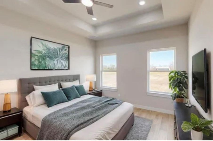 Bedroom with a tray ceiling, light wood-style flooring, recessed lighting, and a ceiling fan Bedroom with a tray ceiling, light wood-style flooring, recessed lighting, and a ceiling fan