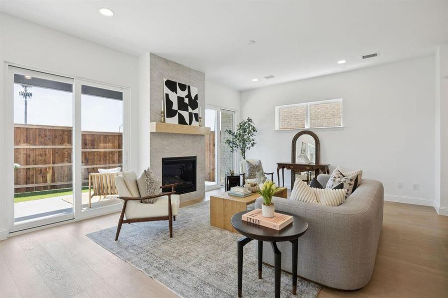 Living area featuring a modern fireplace with a light-colored tile surround and a natural wood mantel