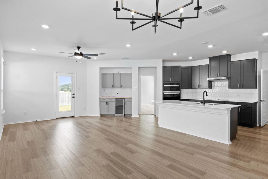 Kitchen with decorative backsplash, a kitchen island with sink, recessed lighting, open floor plan, and a chandelier