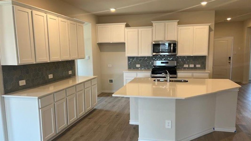 Kitchen with white cabinets, tasteful backsplash, stainless steel appliances, recessed lighting, and a center island with sink Kitchen with white cabinets, tasteful backsplash, stainless steel appliances, recessed lighting, and a center island with sink