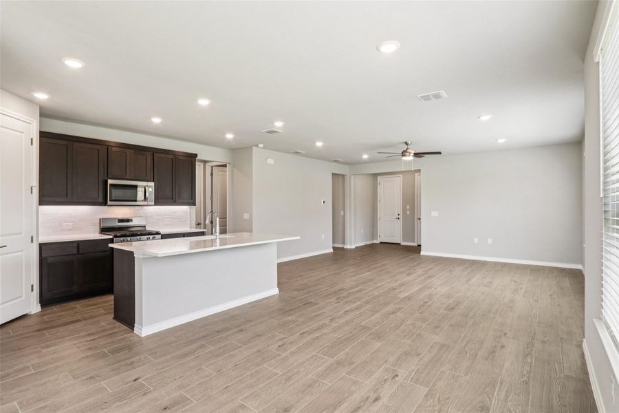 Kitchen featuring light wood-style flooring, a ceiling fan, stainless steel appliances, decorative backsplash, and recessed lighting