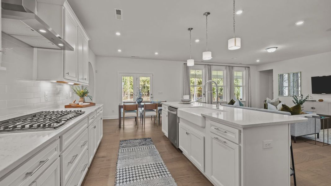 Gourmet kitchen with gas cooktop, vented hood, expansive island with quartz counter tops, in the Townsend Design by DRB Homes