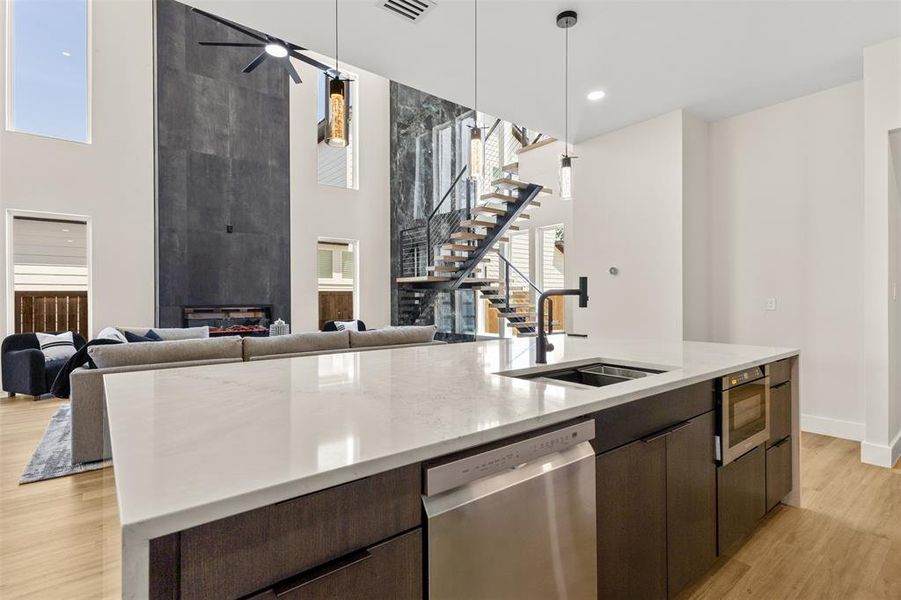 Expansive kitchen island featuring a light-toned countertop, stainless steel dishwasher, and built-in microwave drawer
