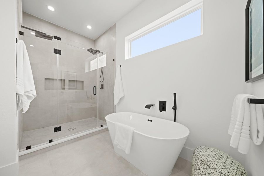 Relax after a long day in the freestanding soaking tub with waterfall faucet, a separate spray wand s and a transom window above allows for natural light to fill the bath.