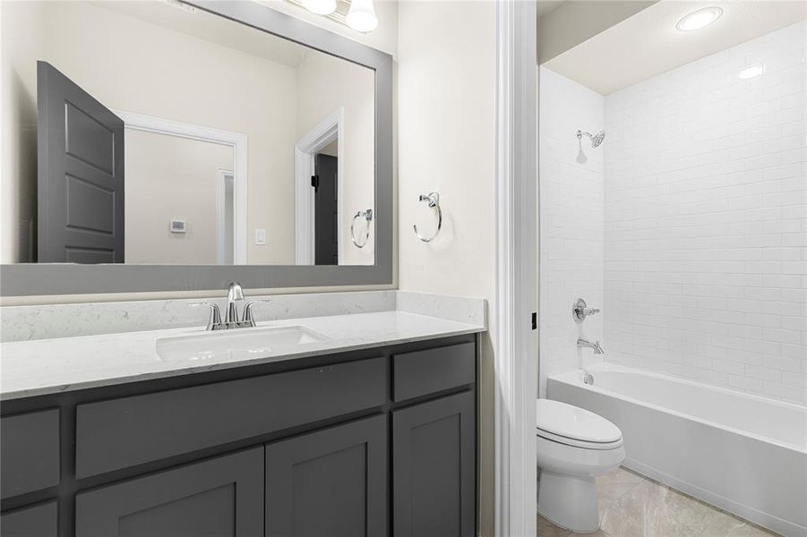 Full bathroom with vanity, tile patterned flooring, tiled shower / bath combo, and toilet