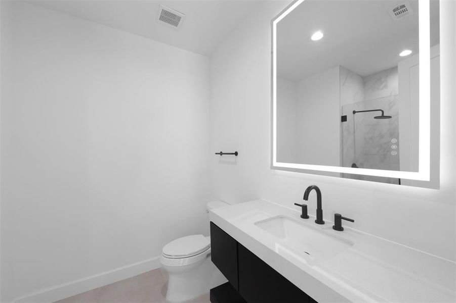 Bathroom featuring vanity, a marble finish shower, light tile patterned floors, and recessed lighting