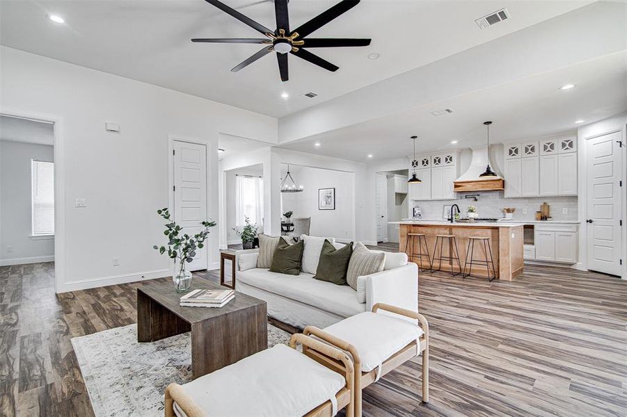 Living room with a healthy amount of sunlight, sink, wood-type flooring, and ceiling fan with notable chandelier