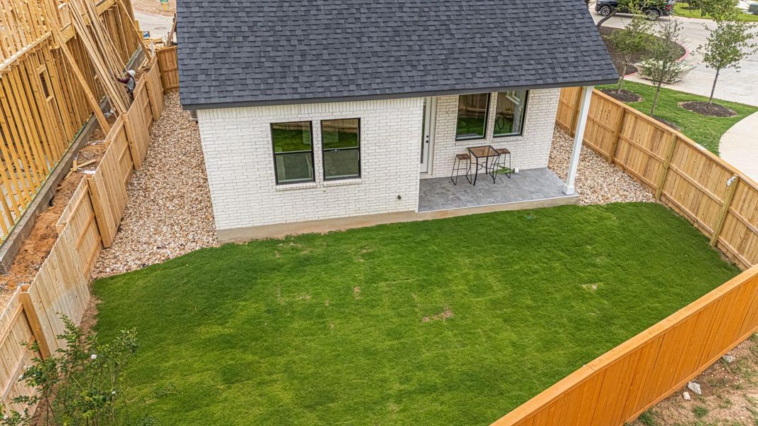 Back of property featuring brick siding, roof with shingles, and a patio