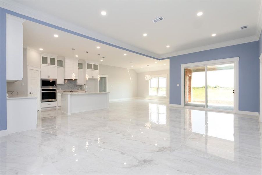 Open concept featuring living room, kitchen, dinning,  ornamental molding, light marble finish floors, and recessed lighting