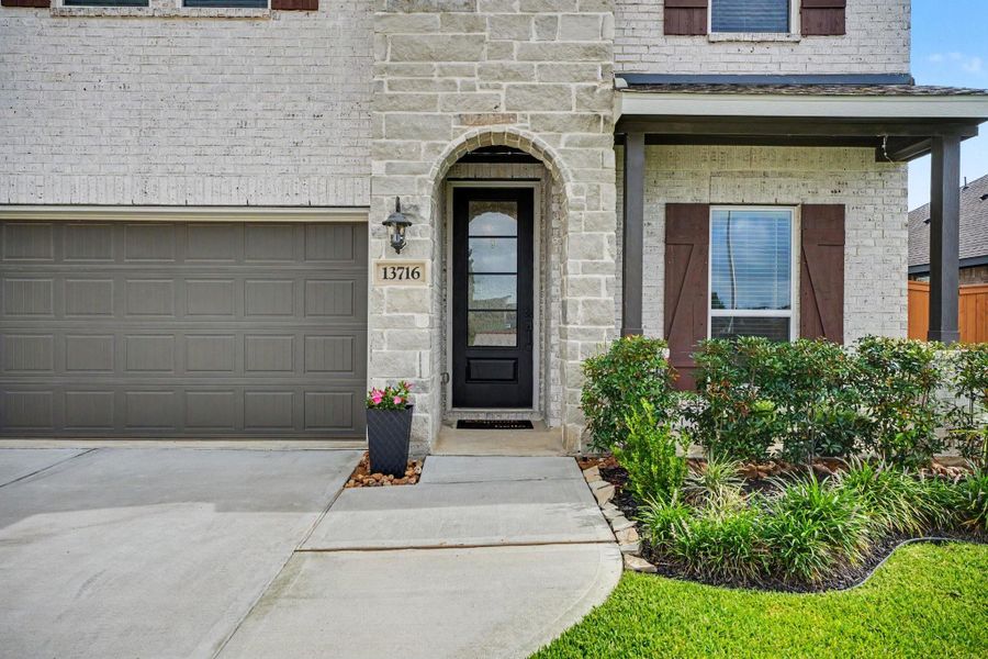 Welcoming covered entry with stone accents, decorative landscaping, and a stylish front door that creates a warm first impression. Welcoming covered entry with stone accents, decorative landscaping, and a stylish front door that creates a warm first impression.