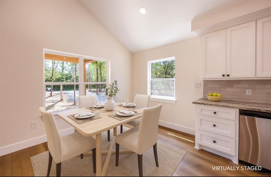 Dining room with light wood-style flooring, recessed lighting, and high vaulted ceiling