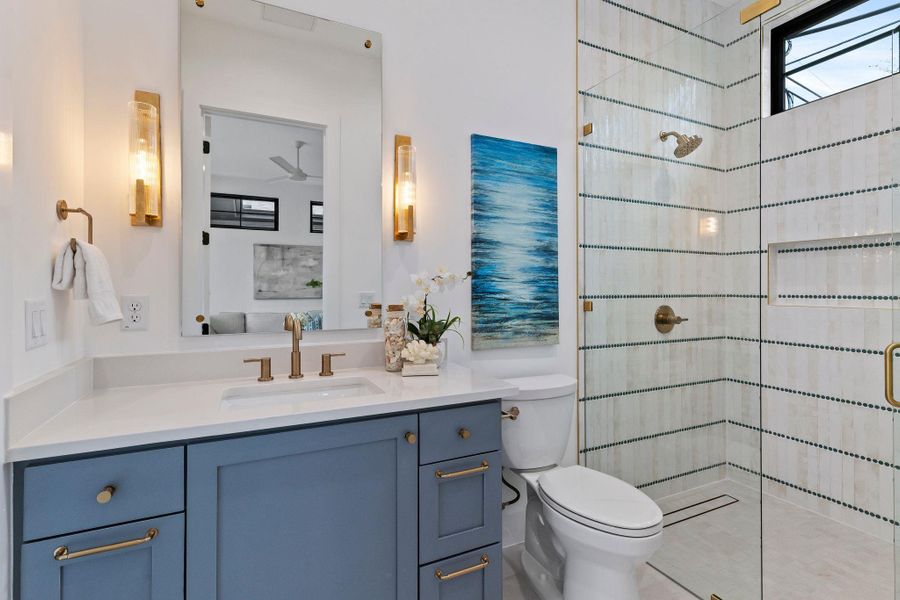 Full bathroom with tiled shower, toilet, vanity, and ceiling fan