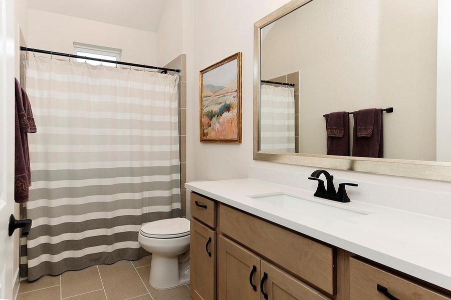 Pretty wood cabinetry, quartz counters, large framed mirror in one of the secondary baths Pretty wood cabinetry, quartz counters, large framed mirror in one of the secondary baths