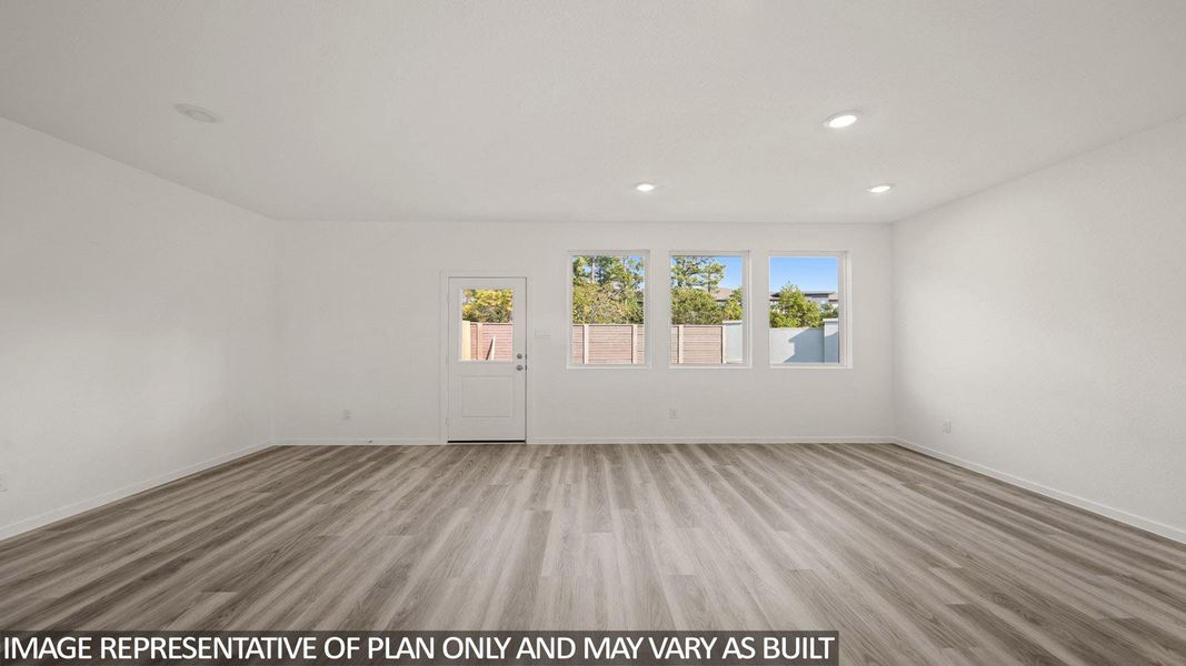 Spacious room featuring wood-finish flooring, white walls, recessed lighting, multiple windows, and a glass-paneled door