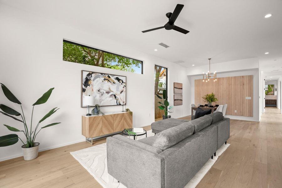 Living room featuring ceiling fan, light wood-style flooring, and hanging lights