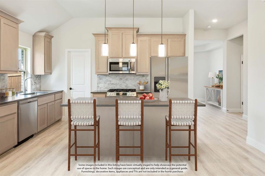 Kitchen with tan cabinets, center island with three bar stools, pendant lights, and stainless steel appliances