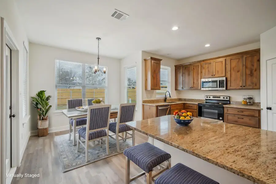 Virtually Staged Kitchen with visible vents, a chandelier, appliances with stainless steel finishes, a kitchen breakfast bar, and light wood-style floors