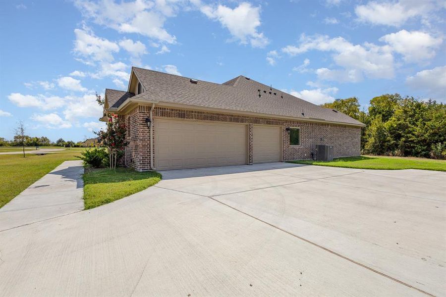 View of property exterior featuring brick siding, a yard, a shingled roof, and concrete driveway View of property exterior featuring brick siding, a yard, a shingled roof, and concrete driveway