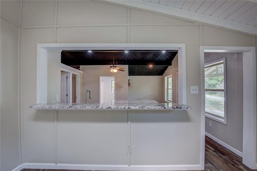 Kitchen with dark wood-type flooring, wood ceiling, lofted ceiling, and light stone countertops