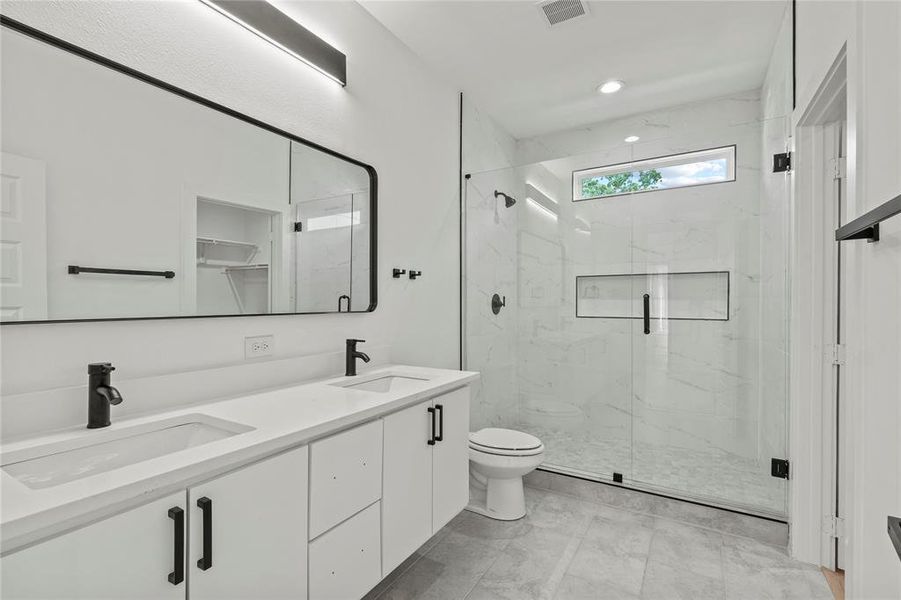 Full bath with toilet, a marble finish shower, double vanity, and recessed lighting Full bath with toilet, a marble finish shower, double vanity, and recessed lighting