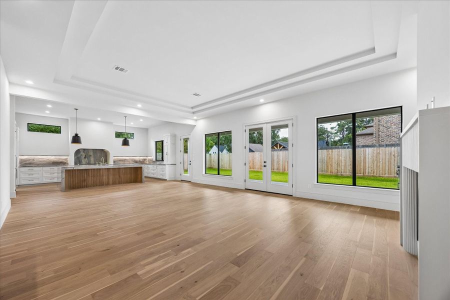 Vaulted tray ceilings and walls of windows fill the open living spaces with natural light while creating a seamless connection to the covered patio and backyard. Thoughtfully designed sightlines keep the kitchen, dining, and living areas connected without sacrificing a sense of scale.