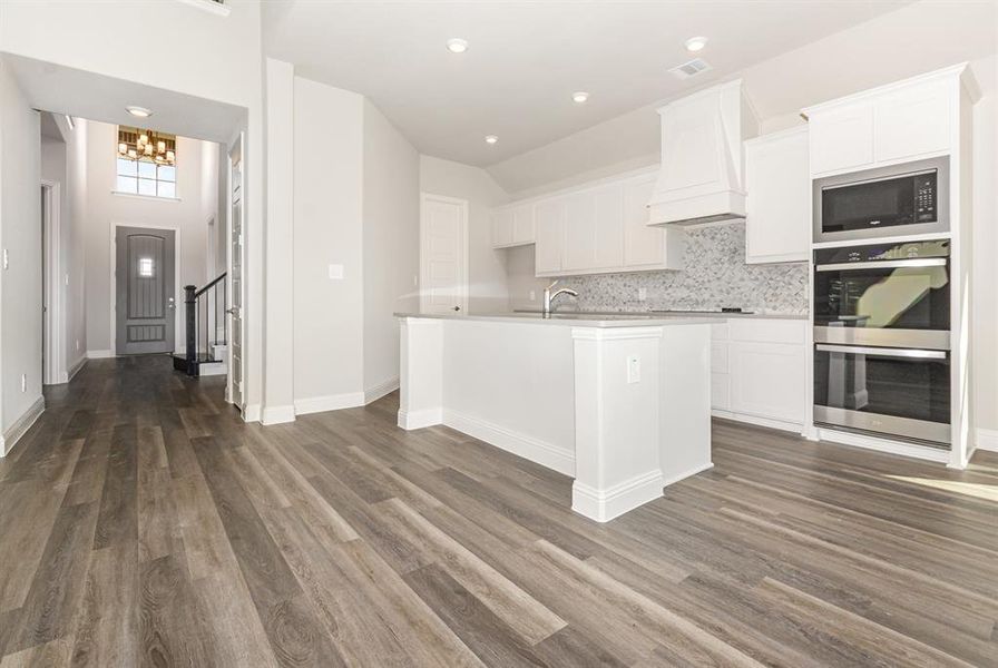 Kitchen featuring decorative backsplash, stainless steel appliances, white cabinetry, a center island with sink, and recessed lighting