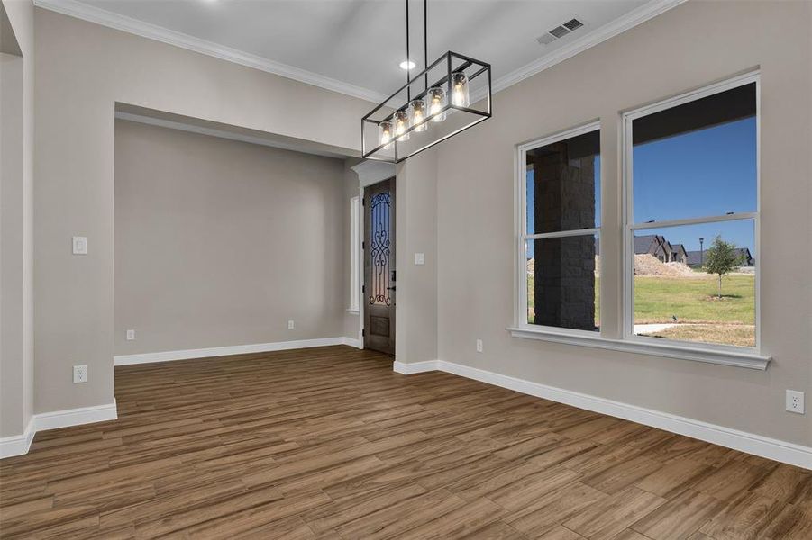 Empty room featuring ornamental molding, wood finished floors, a chandelier, and recessed lighting Empty room featuring ornamental molding, wood finished floors, a chandelier, and recessed lighting