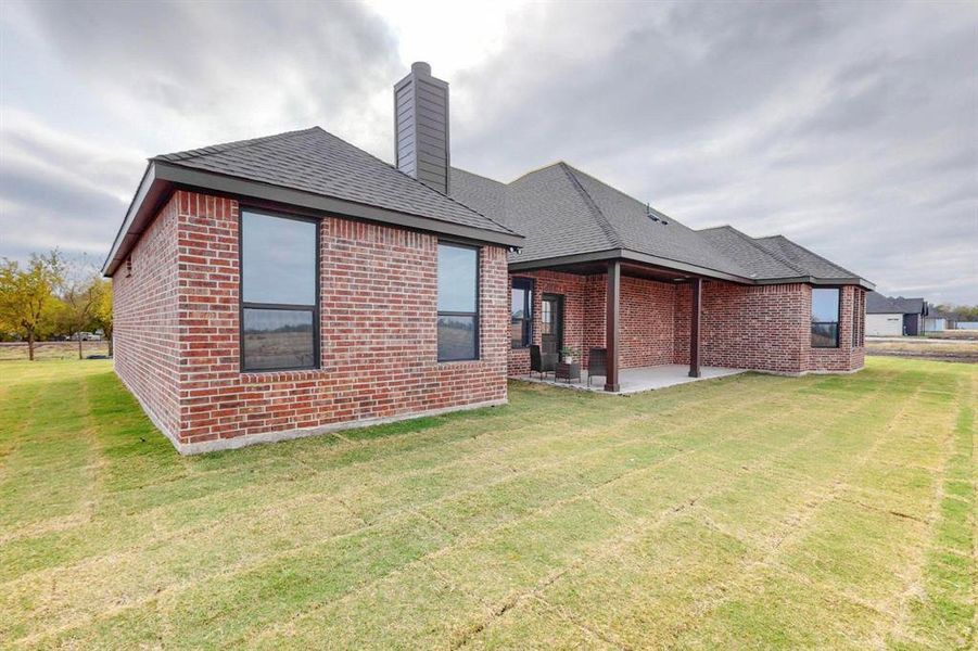 Rear view of property featuring a patio and a lawn