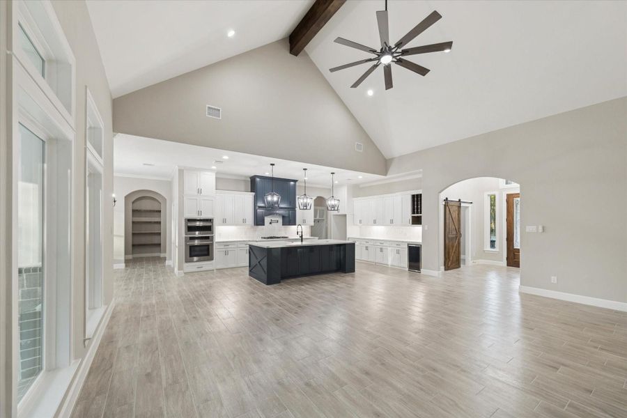 Family room view of hallway to master bedroom on the left, and arched opening shows built-in bookshelf.  Arched opening on the right leads to the entry hall and office.