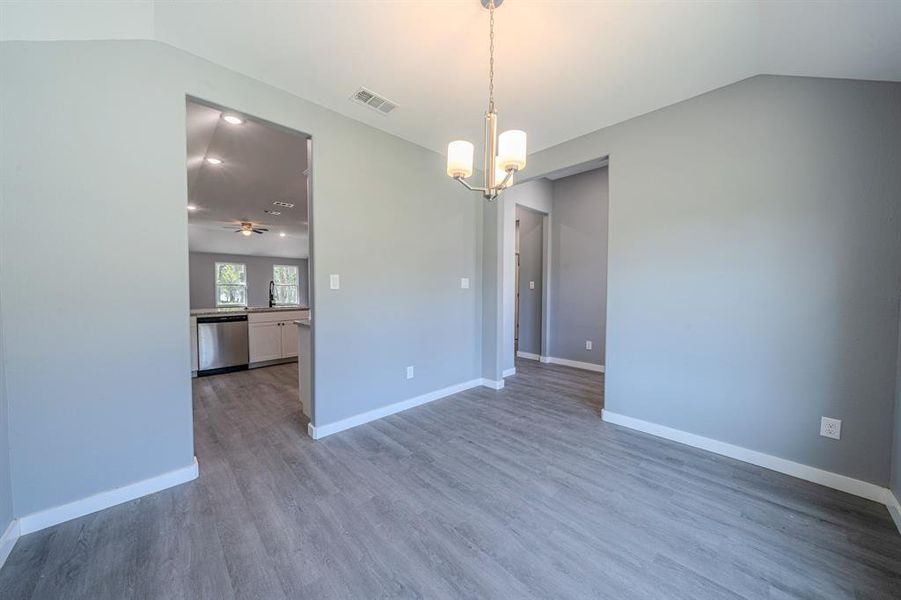Unfurnished room with dark wood-style floors, a chandelier, lofted ceiling, and a ceiling fan Unfurnished room with dark wood-style floors, a chandelier, lofted ceiling, and a ceiling fan