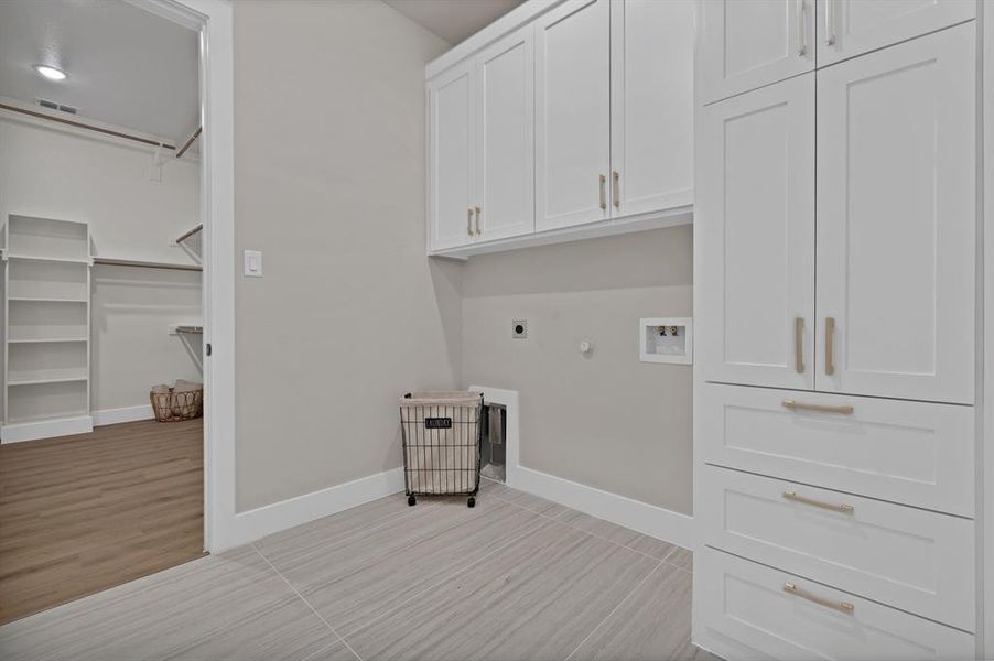 Washroom featuring cabinet space, hookup for an electric dryer, hookup for a washing machine, baseboards, and gas dryer hookup Washroom featuring cabinet space, hookup for an electric dryer, hookup for a washing machine, baseboards, and gas dryer hookup