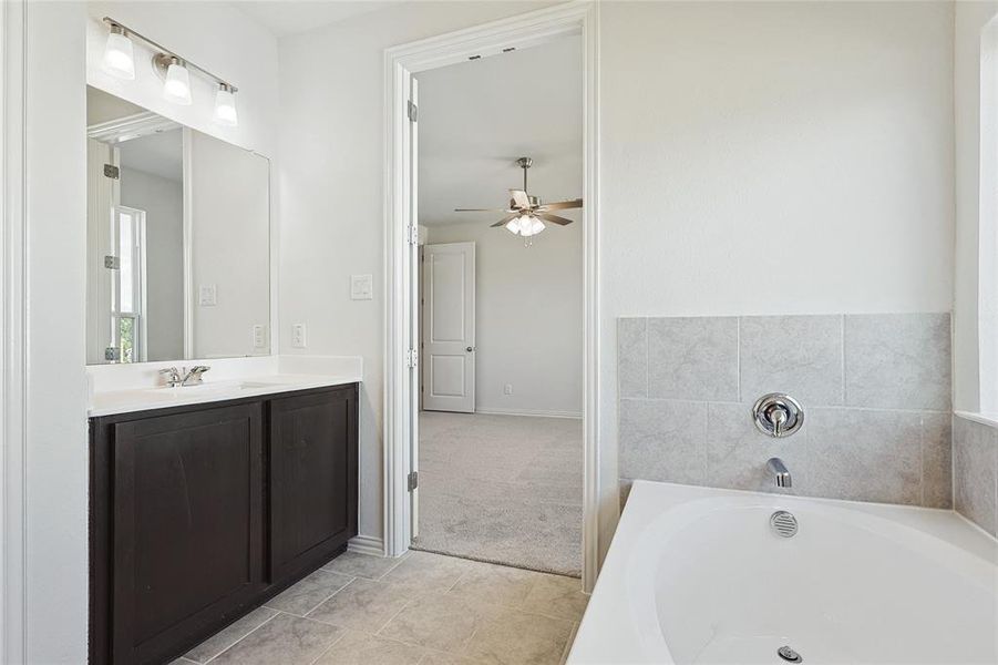 Bathroom with a bath, ceiling fan, tile flooring, and vanity with extensive cabinet space