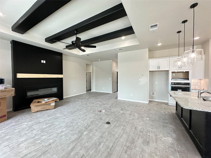 Living area with recessed lighting, a large fireplace, light wood-type flooring, ceiling fan, and a raised ceiling