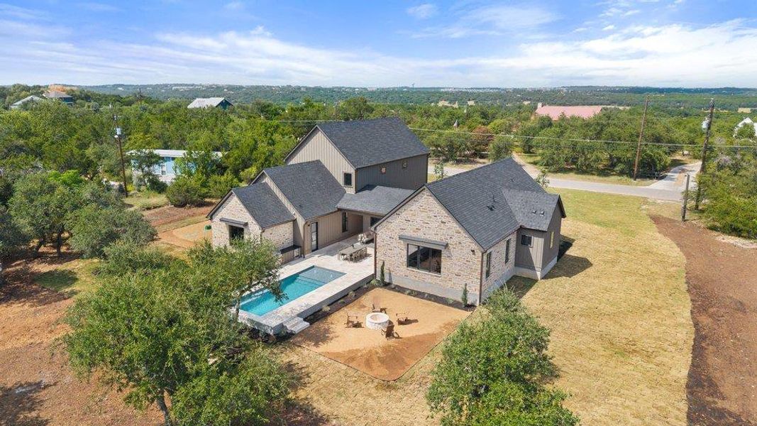 An inviting swimming pool and fire pit area complement this charming modern farmhouse, offering serene outdoor living.