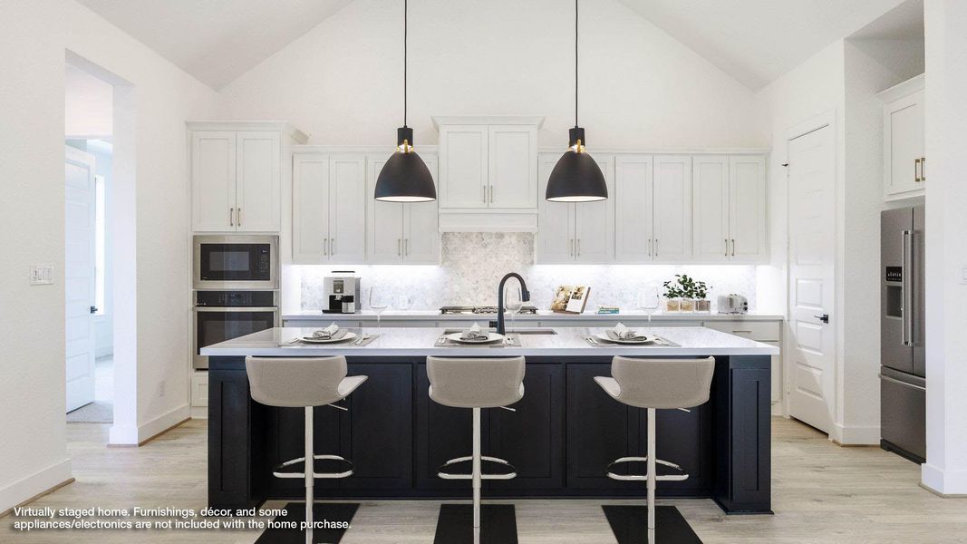 Kitchen with dark cabinets, a breakfast bar area, an island with sink, backsplash, and appliances with stainless steel finishes
