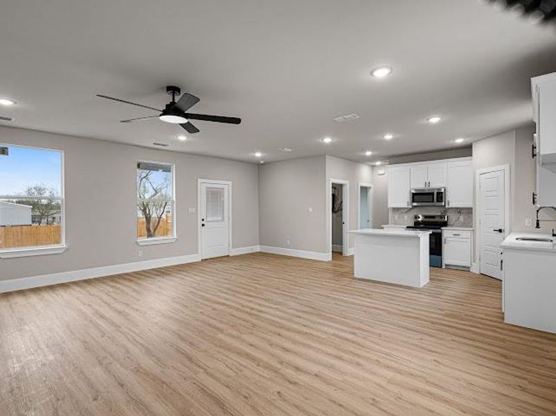 Kitchen with a kitchen island, white cabinets, open floor plan, light wood-style floors, and stainless steel appliances Kitchen with a kitchen island, white cabinets, open floor plan, light wood-style floors, and stainless steel appliances