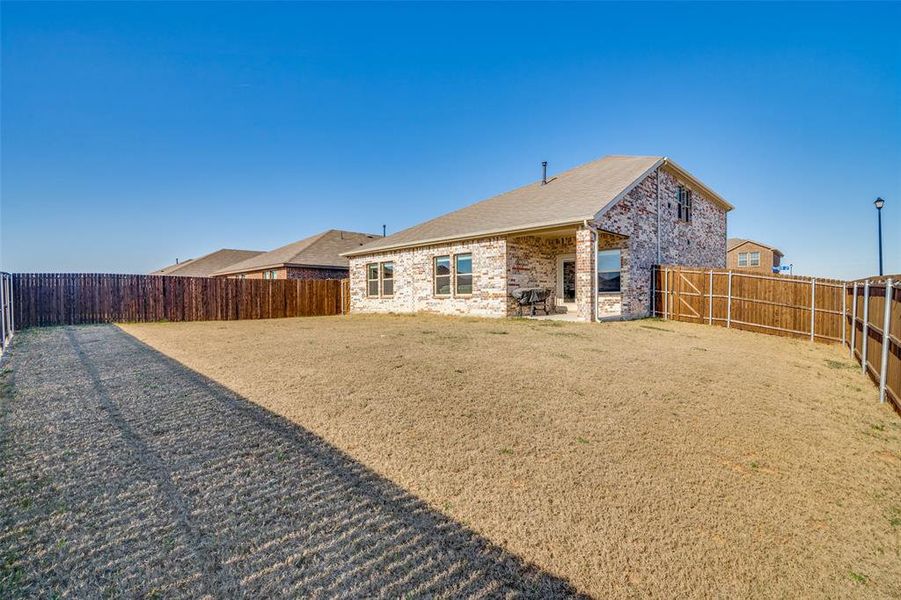 Rear view of property with a patio, a fenced backyard, and brick siding Rear view of property with a patio, a fenced backyard, and brick siding