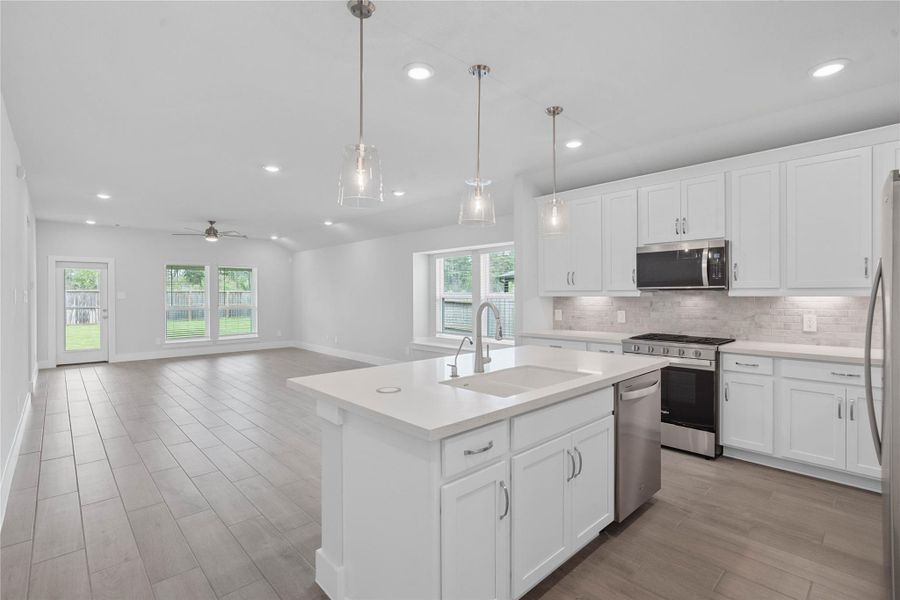 As you step past the entryway, you are immediately welcomed by a bright, open-concept kitchen that serves as the home's focal point. The space feels clean and modern, anchored by a large quartz-topped island that seamlessly connects the cooking area to a long, light-filled living space.