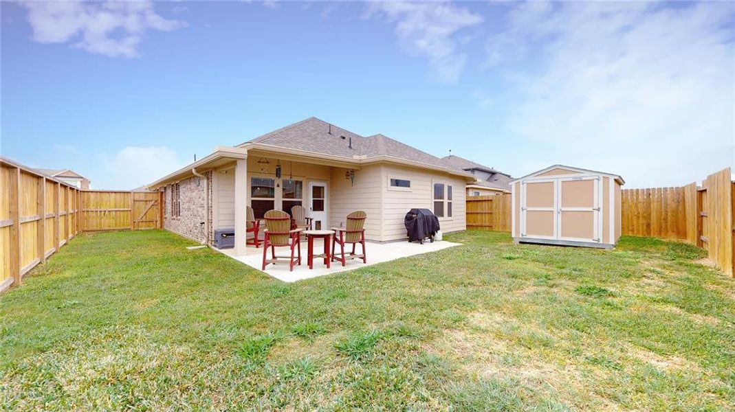 This photo showcases a covered patio with comfortable seating, perfect for relaxation and entertaining. It features an extended concrete pad and overlooks a neatly fenced backyard, providing privacy and a touch of greenery.