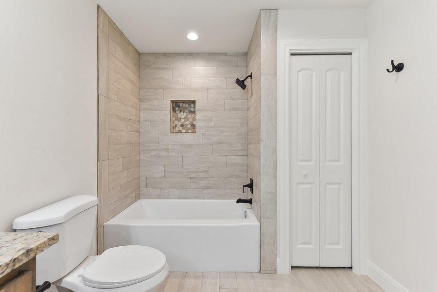 Jack 'n Jill  Full bathroom featuring bathing tub / shower combination, toilet, wood plank tile floors, a closet, and vanity