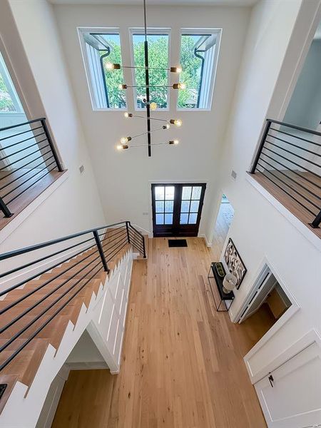 Entrance foyer featuring a chandelier, a high ceiling, light wood finished floors, and french doors Entrance foyer featuring a chandelier, a high ceiling, light wood finished floors, and french doors