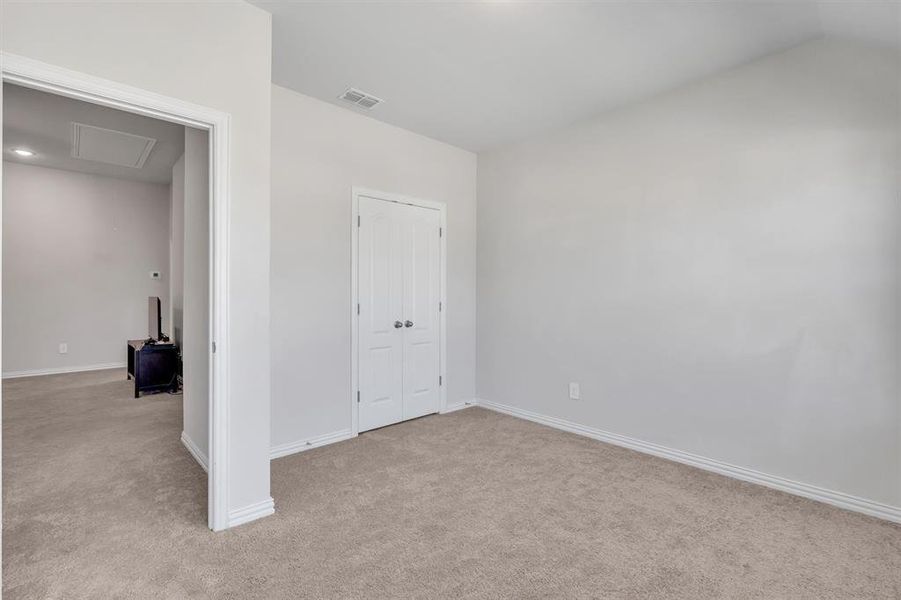 Unfurnished bedroom featuring lofted ceiling and light carpet