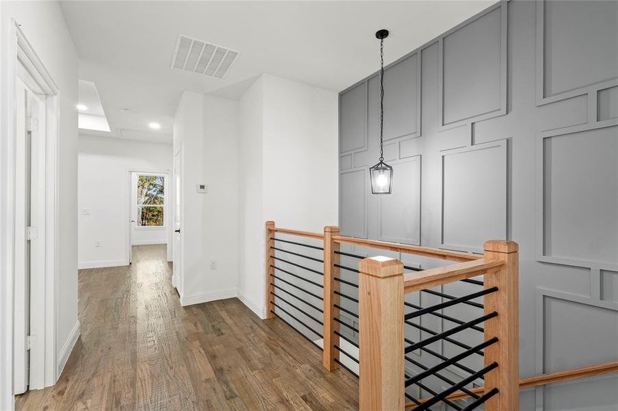 Corridor with an upstairs landing, wood finished floors, and recessed lighting