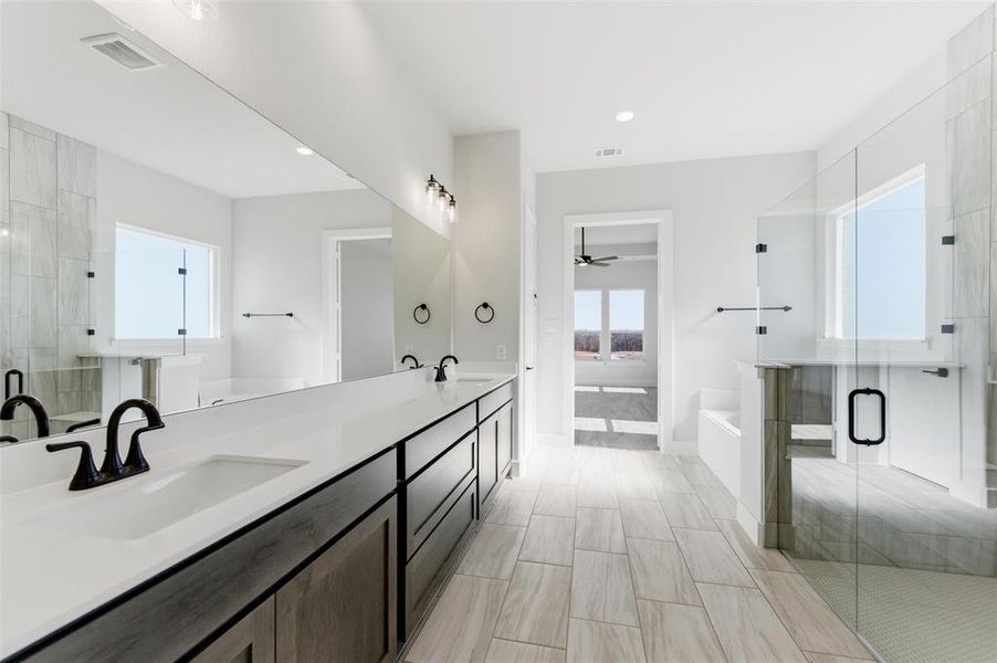 Full bathroom featuring a shower stall, a garden tub, double vanity, and ceiling fan