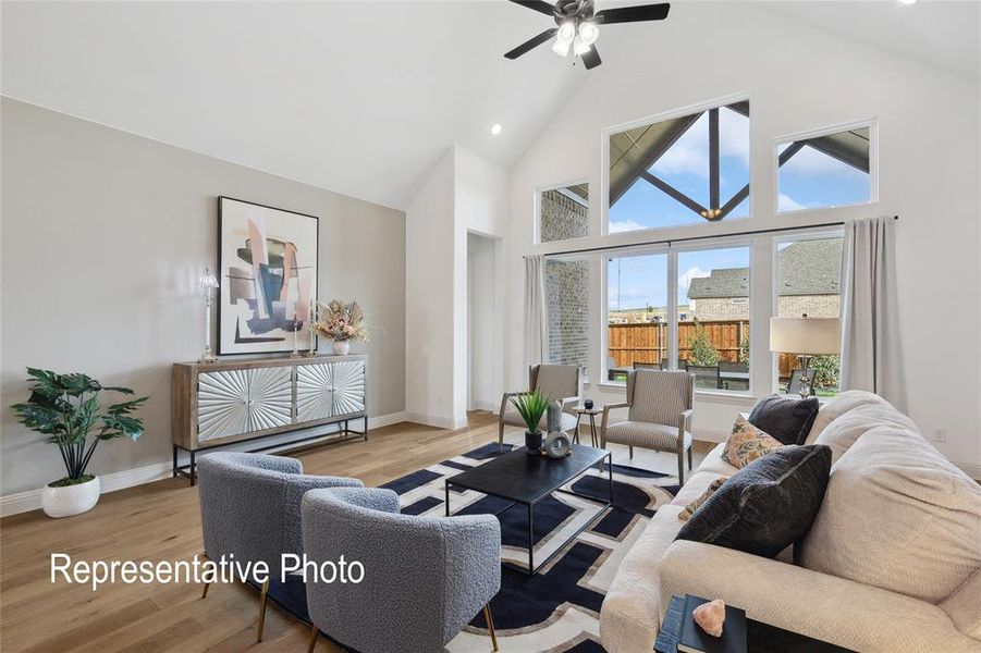 Vaulted ceiling living space featuring a ceiling fan, wood-finish flooring, and expansive windows